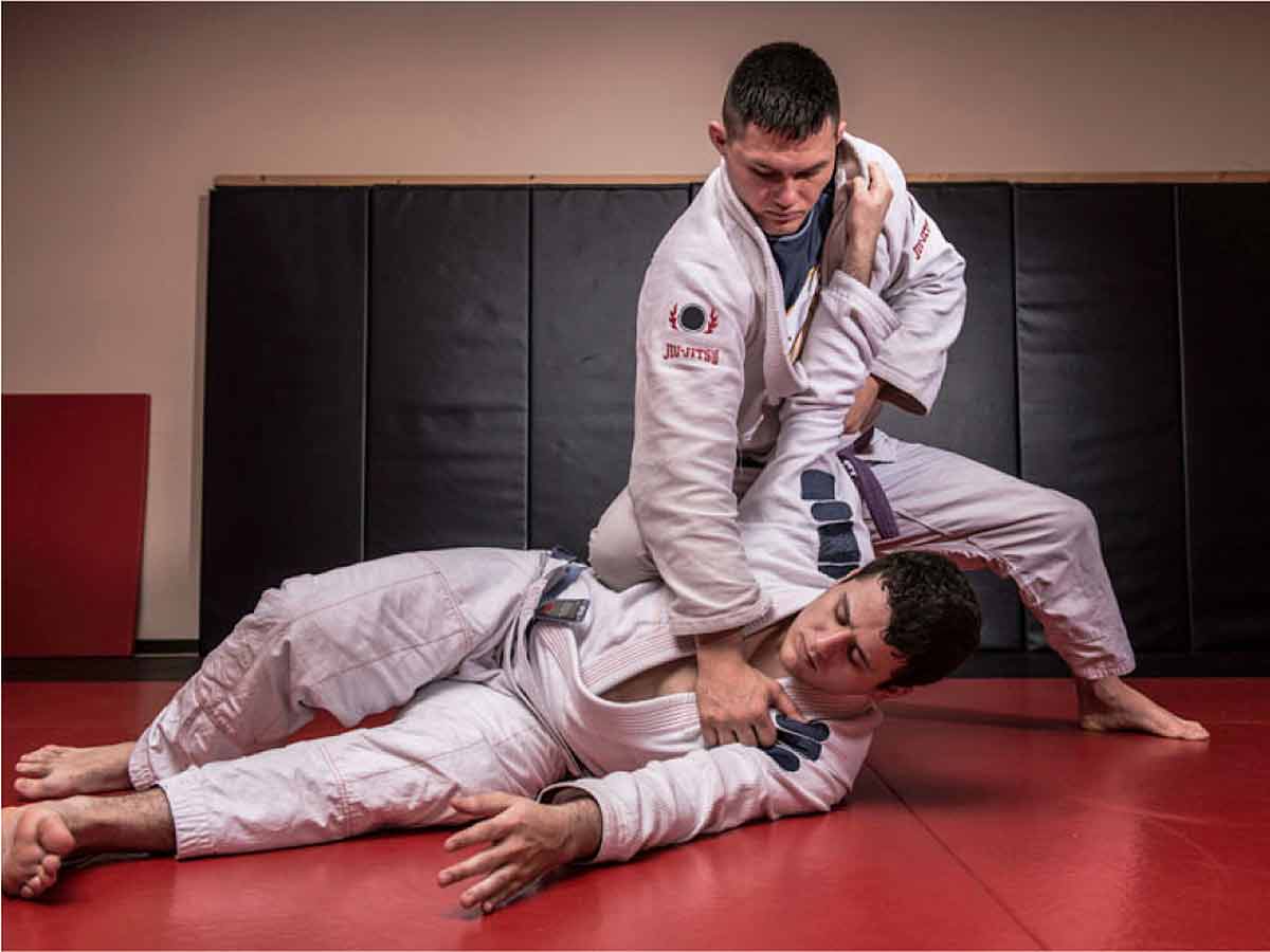 Two men in white robes engage in bjj grappling.