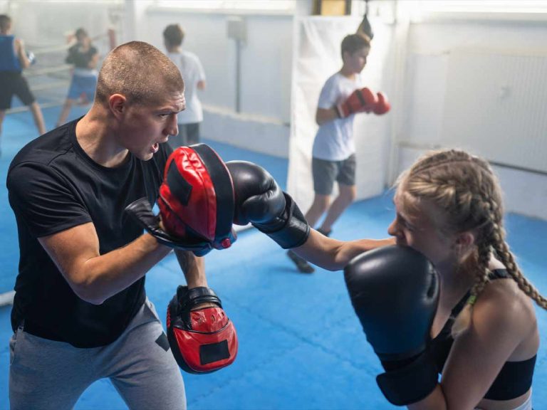 A young girl trains kickboxing with a male trainer.